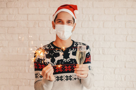 Young male doctor in Santa hat, medical face mask, protective gloves hold red heart in hands. Happy man surgeon in protective face mask show heart sign with fingers. Christmas donation, charity, helpの写真素材