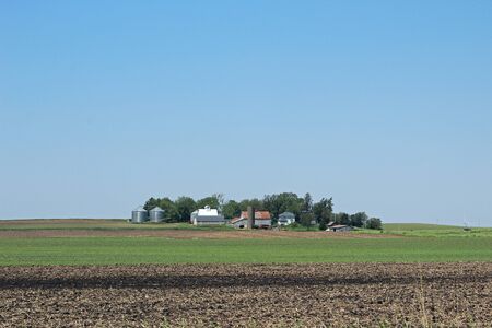 Farm in distance with blue sky and fieldの写真素材