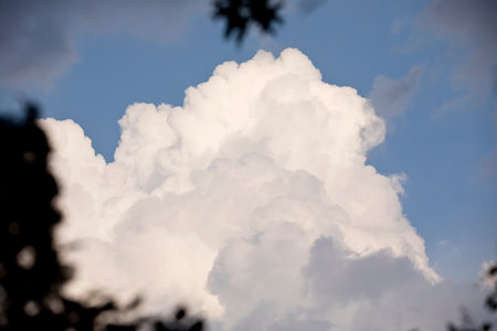 White, fluffy cumulonimbus cloud in a bright blue sky on a spring evening in Iowa.