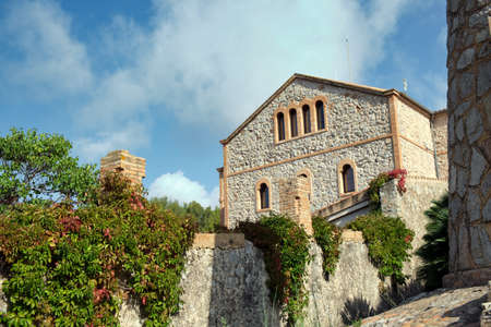 Typical Catalan architectural house built of stone and bricks with a wall and hanging plants, surrounded by nature in the Castelldefels Natural Park. Cloudy sky. Shot natural morning light.のeditorial素材