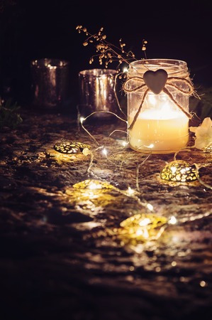 Romantic still life with candlelight, decorative garlands and flowers.の写真素材