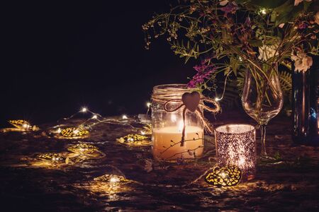 Romantic still life with candlelight, decorative garlands and flowers. Place for text, dark background.の写真素材