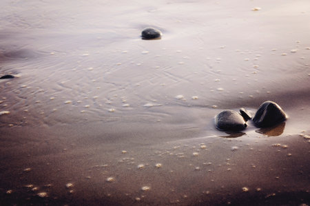 Close up view of coastline with dark sand and small pebbles