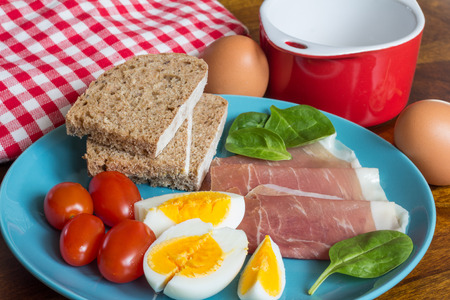 boiled eggs with ham and bread breakfast on blue plateの写真素材