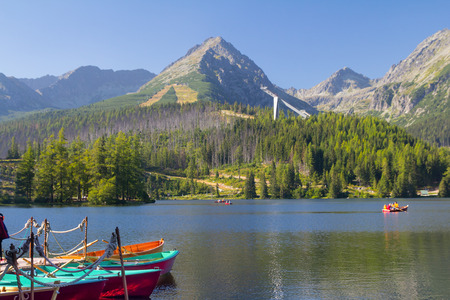 Tatras mountains of Slovakia, near Poland, from view of boats in lake under hazy ble sky and forests in the foothillsの写真素材