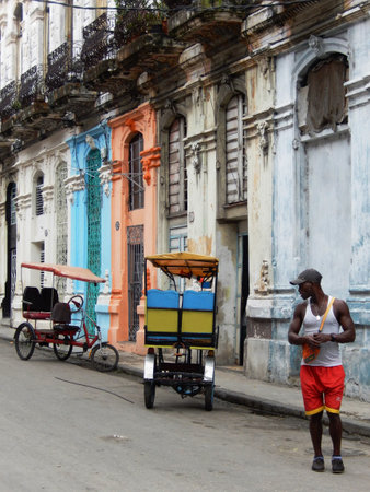 Havana, Cuba - January 31, 2016: Two taxi rickshaws parked in a street with buildings with colorful facades in Old Havana, Cubaのeditorial素材