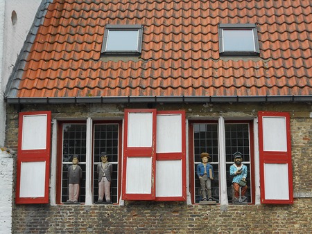 Bruges, Belgium - April 29, 2014: Figures of Laurel and Hardy and local people placed on the windows of a building on a canal in Bruges, Belgium.のeditorial素材