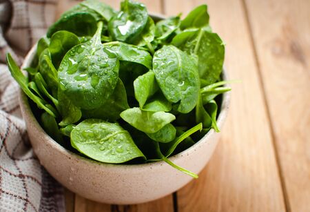 Close-up of baby spinach in a bowl on wooden tableの写真素材