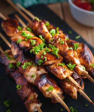 Close-up of homemade honey and beer BBQ chicken skewers with fresh parsleyの写真素材