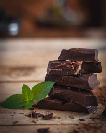 Close-up of stacked dark chocolate with fresh mint on wooden backgroundの写真素材
