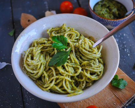 Close-up of spaghetti pasta with pesto sauce on dark background
