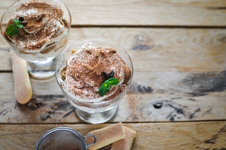 Classic tiramisu cake in a glass with fresh mint, on wooden backgroundの写真素材