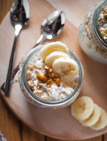 Close-up of homemade banana oats in a glass jar on wooden background, top viewの写真素材