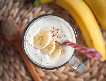 Close-up of banana and flax seeds smoothie in a glass on wooden background, top viewの写真素材