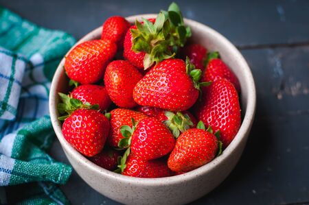 Close-up of fresh strawberries in a bowl on wooden backgroundの写真素材