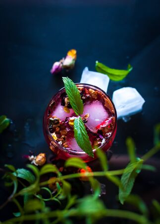 Close-up of homemade flower ice tea in a glass with fresh mint, on dark background, top viewの写真素材