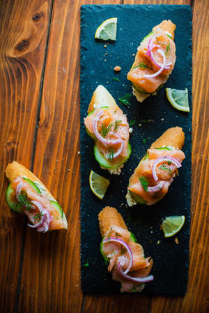 Smoked salmon on a baguette with cream cheese, cucumber, pickled red onion and fresh dill, top viewの写真素材