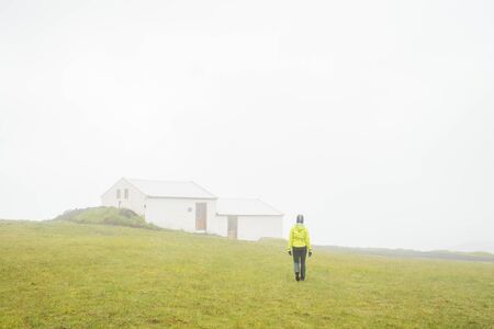 Person walking on green meadow in fog in Icelandの写真素材