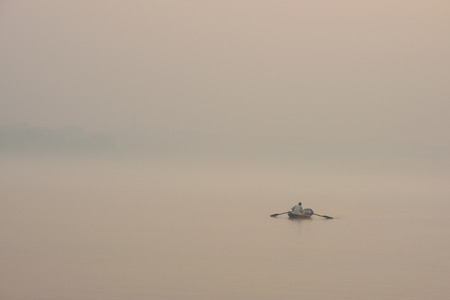 Isolated boat at sunrise over Ganges river bank near holy Varanasi city in Indiaの写真素材