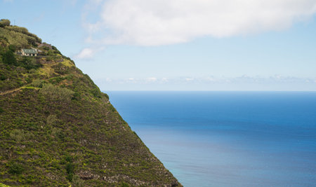 Isolated house on a cliff high above coastline in Madeiraの写真素材