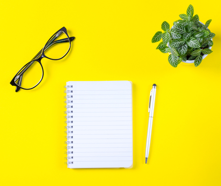 Workspace with notepad and pen on yellow background.の写真素材