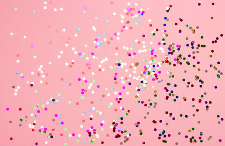 Festive pastel pink background with metallic confetti.の写真素材