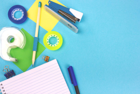Top view of bright light blue office desk with school supplies. Back to school concept. Copy space...