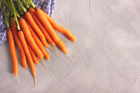 Fresh raw whole carrots on gray betonlook background. Top view. Flat lay style. Copy space for your text.の写真素材