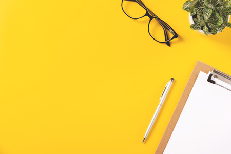Top view of creative workspace with yellow background. Flat lay style. Place for text.の写真素材