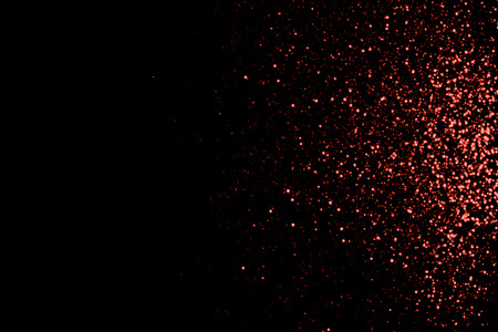 Abstract living coral bokeh texture on black background. Defocused sparkles. Color of the year.の写真素材