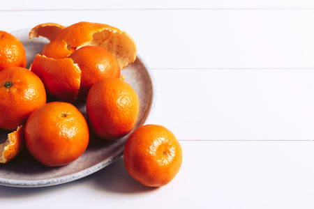 Fresh mandarins on a gray plate on a white wooden table. Copy space.の写真素材