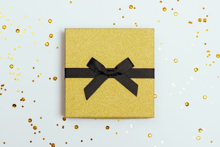 Beautiful festive white background with stylish golden gift box and confetti. Top view.の写真素材