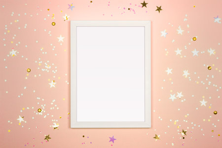 Festive background with blank white photo frame on beige pastel backdrop. Mock up for photo or text. Top view. Flat lay style.の写真素材