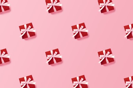 Festive pattern of red gift boxes with pink ribbon on pink background. Christmas, Valentines day or birthday concept. Minimal festive concept.の写真素材