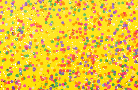 Scattered confetti on yellow background. Holiday decoration concept. Restive backdrop for your design.の写真素材