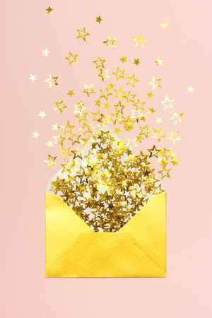 Golden star shaped confetti pouring out of golden envelope on pink background. Correspondence concept.の写真素材
