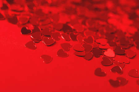 Beautiful festive background with red metallic heart shaped confetti. Valentines day background. Copy space for your text. Selective focus.の写真素材