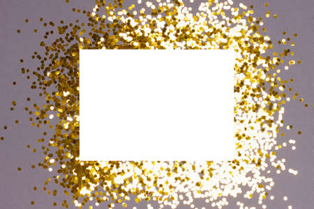 Festive background with blank white paper card with golden confetti on gray background. Holiday or Invitation concept. Place for text. Flat lay, view from above.の写真素材
