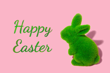 Easter green grass bunny on pink background. Minimal greeting card concept with text.の写真素材