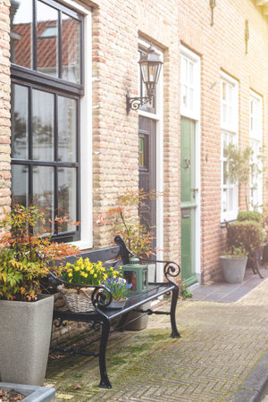 A bench next to the front door of a house with flower decoration.の写真素材