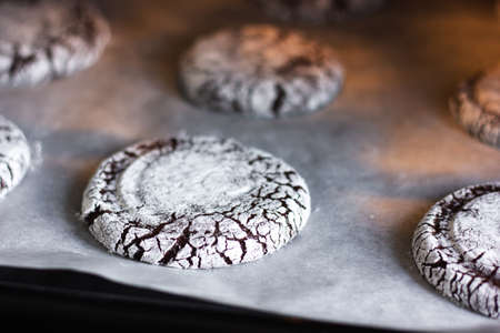 Batch of chocolate crinkle cookies on a parchment paper.の写真素材