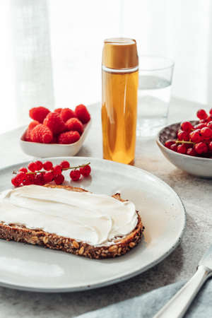 Slice of whole grain bread with soft cheese and honey on top served with fresh berries. Healthy breakfast concept.の写真素材
