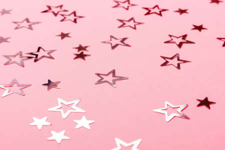 Festive pastel pink background with metallic confetti.の写真素材