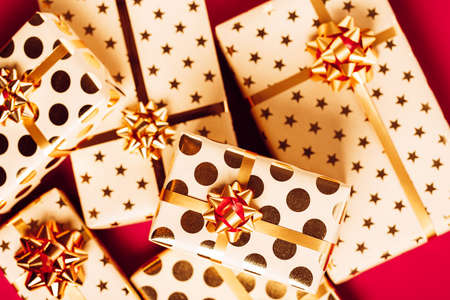 Gift boxes with golden bows on red background.の写真素材
