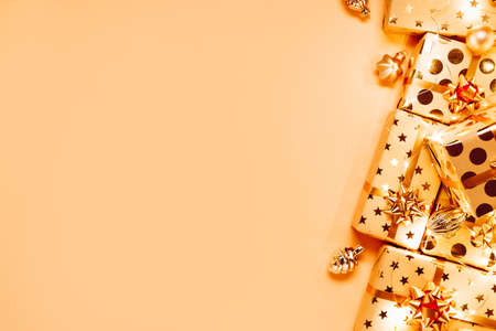 Gift boxes with golden bows, Christmas tree toys and lights on beige background.の写真素材