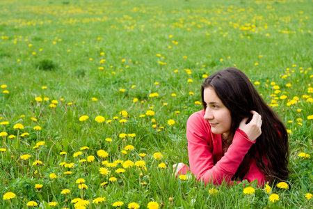 smiling dreaming girl lying among dandelions