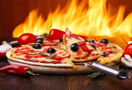 Hot pizza with oven fire on backgroundの写真素材