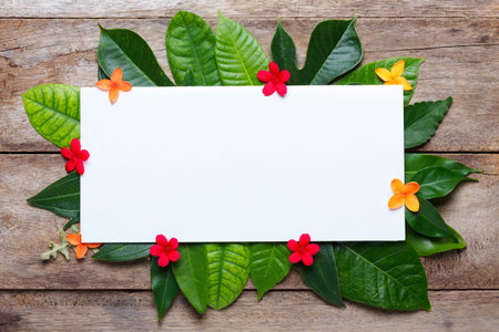 Summer leaves with flowers on wooden background with blank place for text