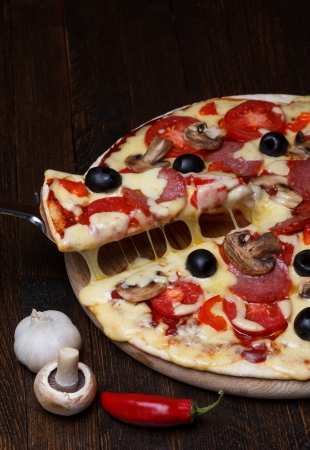 Hot pizza slice lifted, with melting cheeseの写真素材