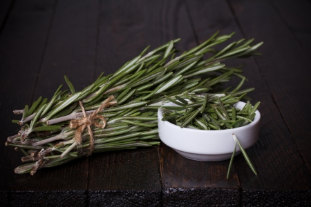 Ripe rosemary bunch and bowl on rustic wooden tableの写真素材